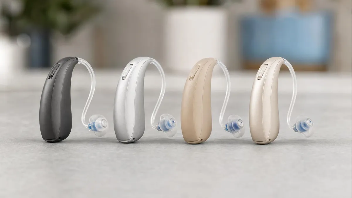 Four modern hearing aids of different styles lined up side by side
